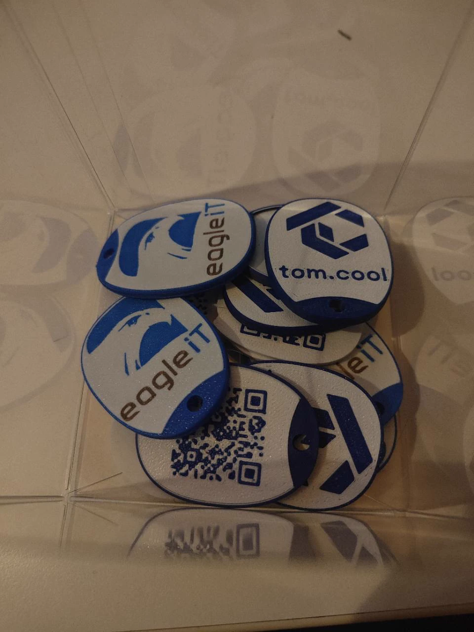 Een reeks blauw-witte sleutelhangers met logo en QR-code
